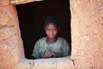 Girl looking out a window of a hut in a village in the Tsaranoro Valley [madagascar_6050]